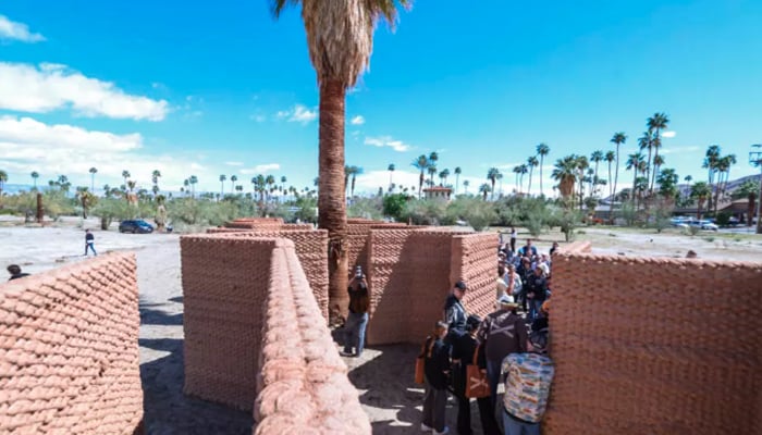 Visitors walk through Ronald Raels Adobe Oasis, which used a huge robotic arm to 3D-print walls of clay and straw in the traditional adobe style. — AFP