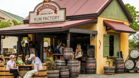 Getty Images/Debbie Ann Powell A shack selling Appleton Estate Rum with tourists sat outside.
