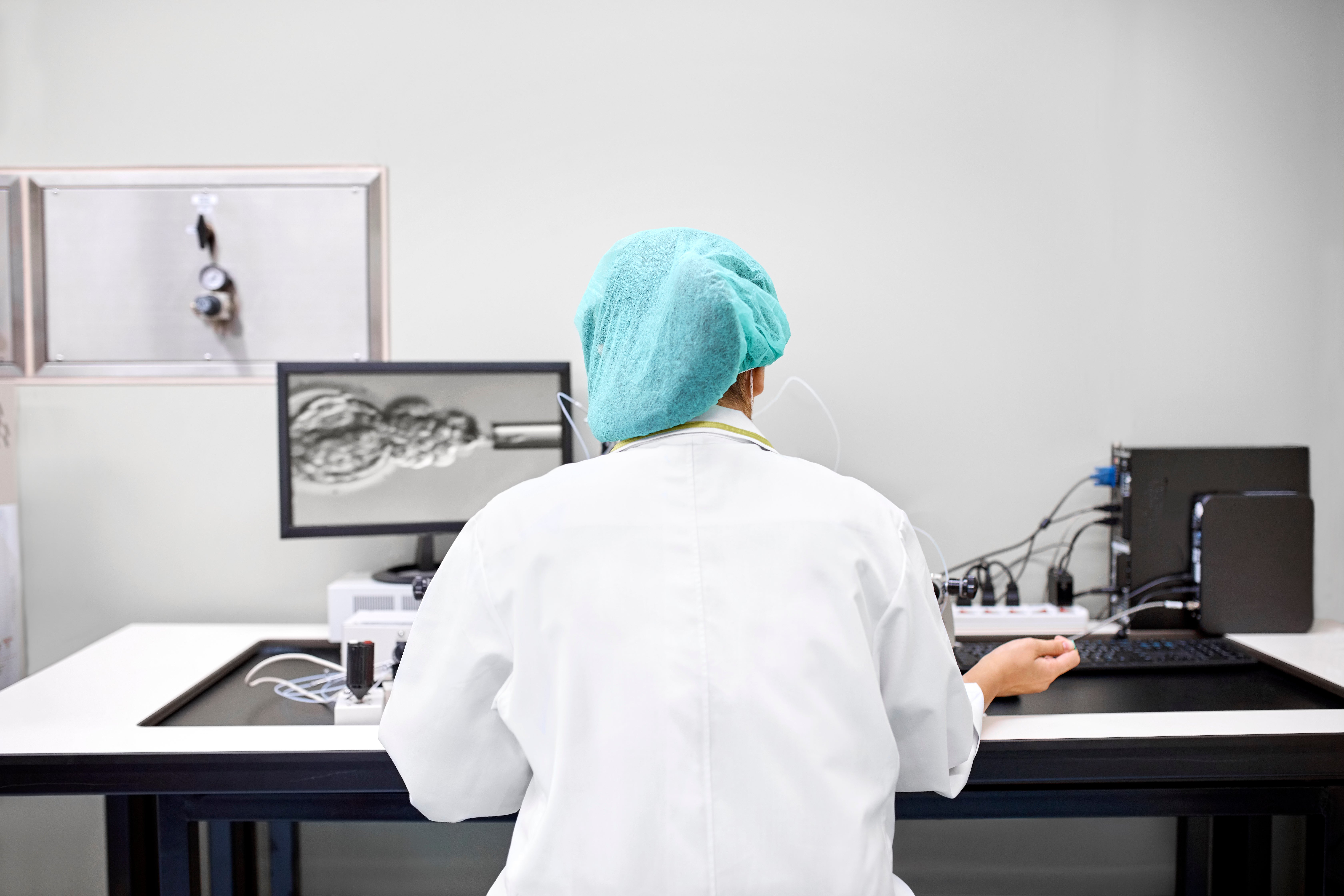 A laboratory technician performing in vitro fertilization of a human egg