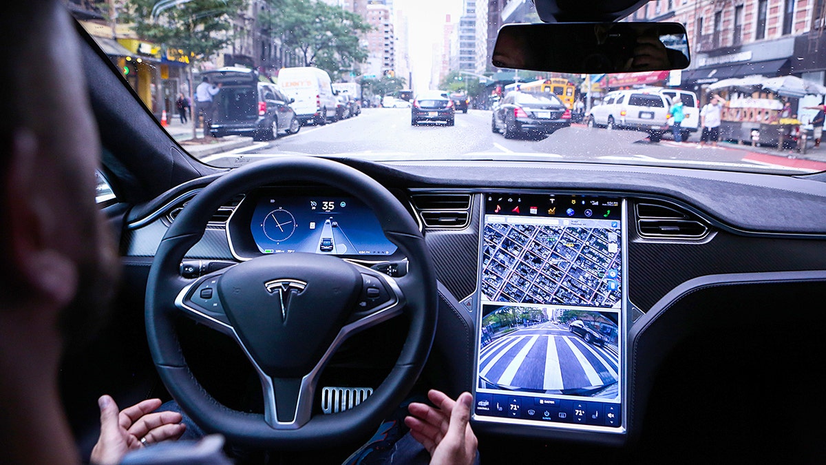 A man using Tesla's full self driving feature on a road